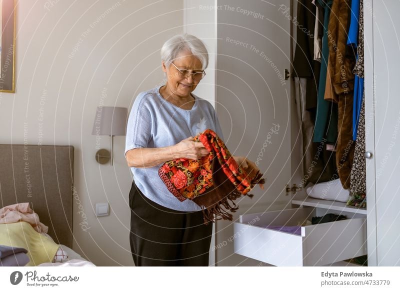 Senior woman tiding up her wardrobe alone at home domestic life elderly female grandma grandmother grey hair house indoors lifestyle mature old older one person