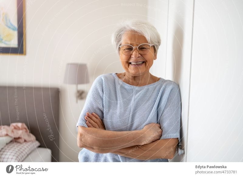 Portrait of smiling senior woman at home glasses eyeglasses spectacles alone domestic life elderly female grandma grandmother grey hair house indoors lifestyle