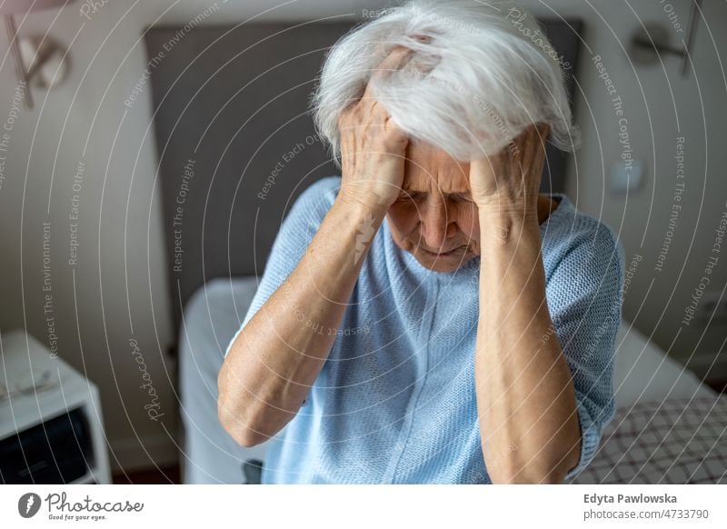 Senior woman covering face with her hands grief grieving depressed depression sad upset dementia mourning loneliness headache migraine miserable unhappy