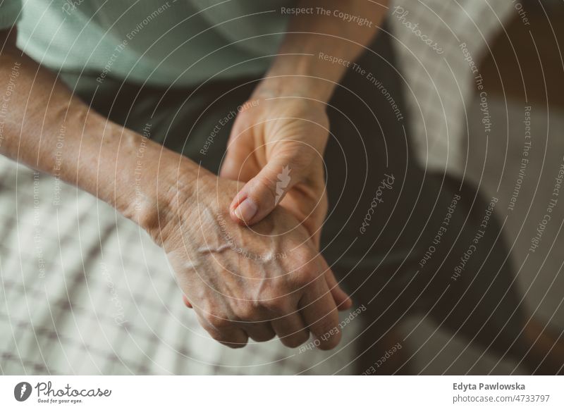 Senior woman with arthritis rubbing hands rheumatism stiff joints massaging wrist osteoporosis wrinkled skin wrinkles close up disease illness unwell health