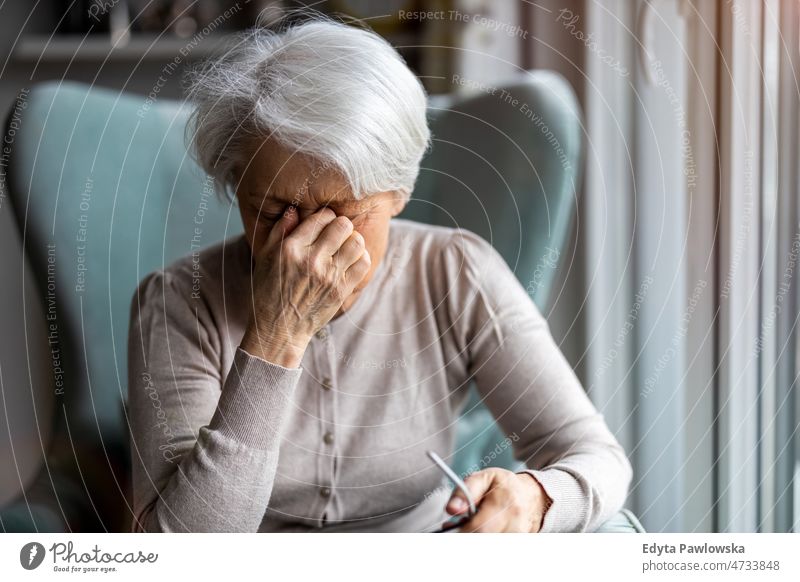 Senior woman suffering from a headache alone at home domestic life elderly female grandma grandmother grey hair house indoors lifestyle mature old older