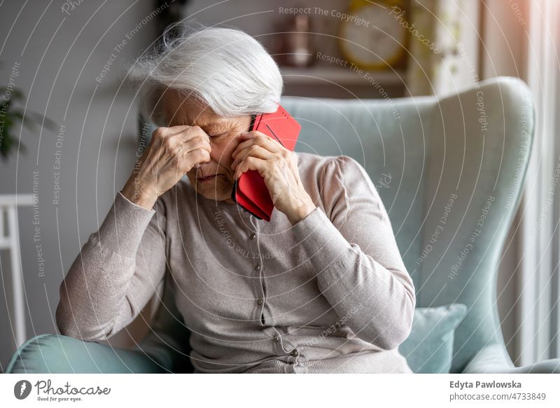 Senior woman feeling pain while consulting doctor on her smart phone alone at home domestic life elderly female grandma grandmother grey hair house indoors