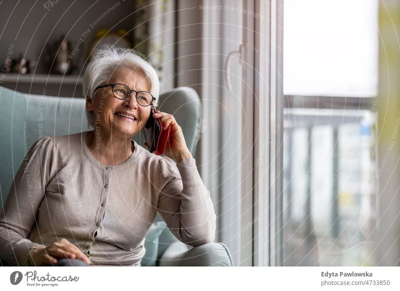Senior woman using mobile phone at home glasses eyeglasses spectacles alone domestic life elderly female grandma grandmother grey hair house indoors lifestyle