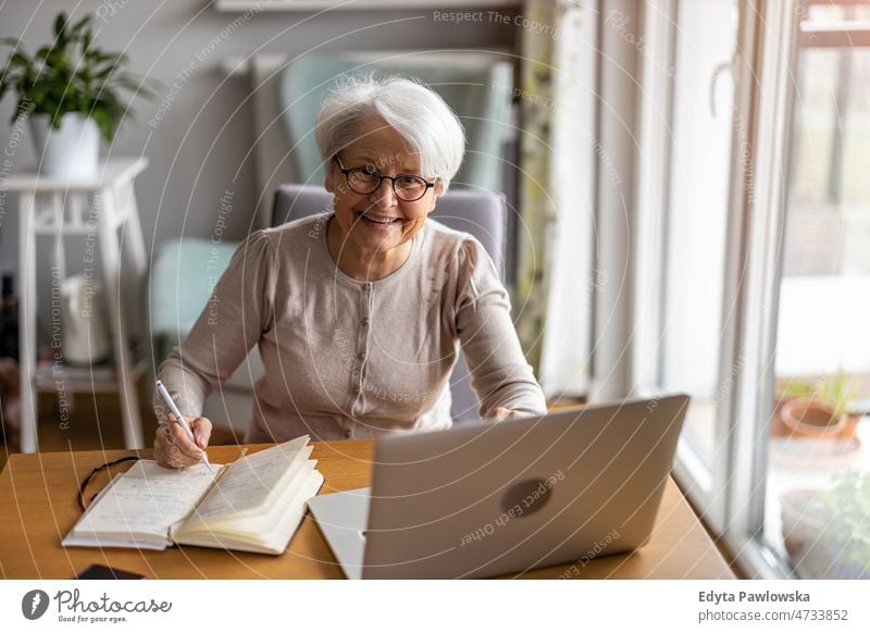 Senior woman using laptop at home glasses eyeglasses spectacles alone domestic life elderly female grandma grandmother grey hair house indoors lifestyle mature