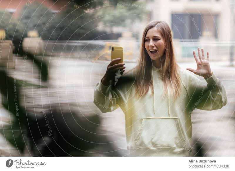 Pretty caucasian woman with smartphone has good time outdoor. portrait of trendy millennial girl with blonde hair wears fashionable clothing mobile phone