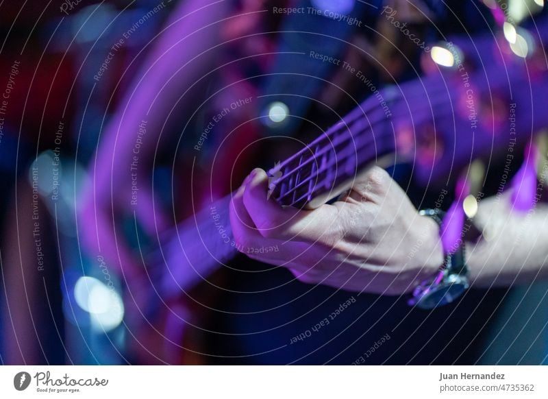 unrecognizable person. Plucking the strings of the electric guitar at a concert plucking left hand bass band musical musician sound play performance performer