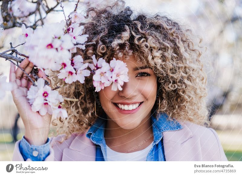 smiling hispanic woman with eyes closed in park enjoying sunny day. Spring flowers background dancing curvy body positivity afro happy spring size portrait
