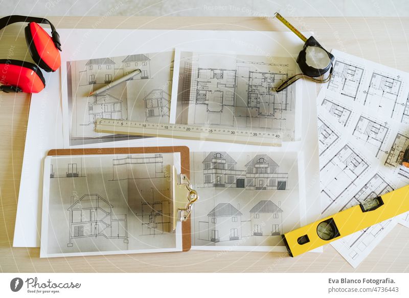 top view of blueprints, ear defenders, level and tools on architect workspace at construction site home meter insulating real state house yellow table build