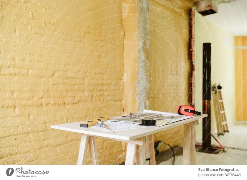 blueprints, ear defenders, protection glasses and tools on architect workspace at construction site home level meter insulating real state house yellow table