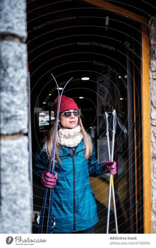 Lady with skis leaving building woman skier pole ski resort warm clothes active equipment rest stick lifestyle female lady ready prepare weekend casual pastime