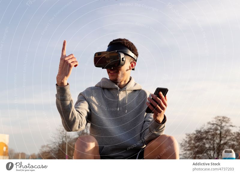 Man in VR headset with smartphone in city man vr cyberspace simulate explore street browsing futuristic index finger virtual reality digital male modern gadget