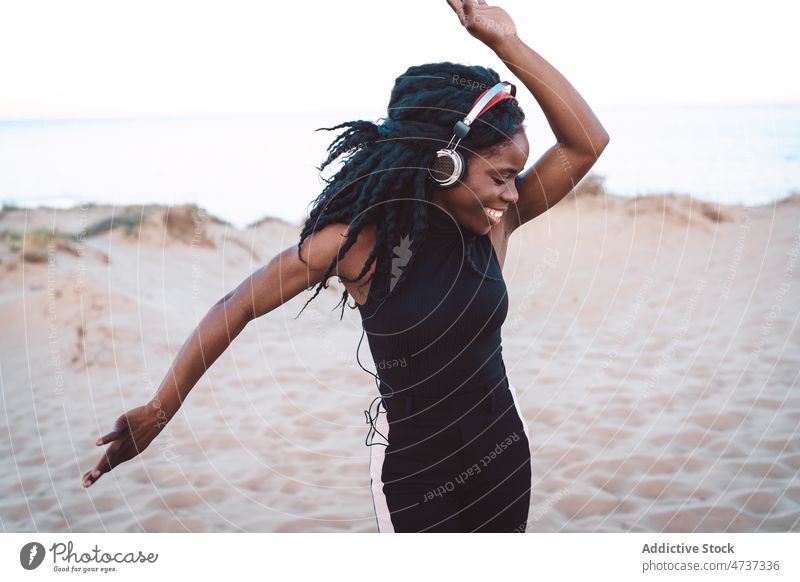 Carefree black woman listening to music on beach dance song headphones summer seashore having fun female ethnic african american carefree freedom enjoy cheerful