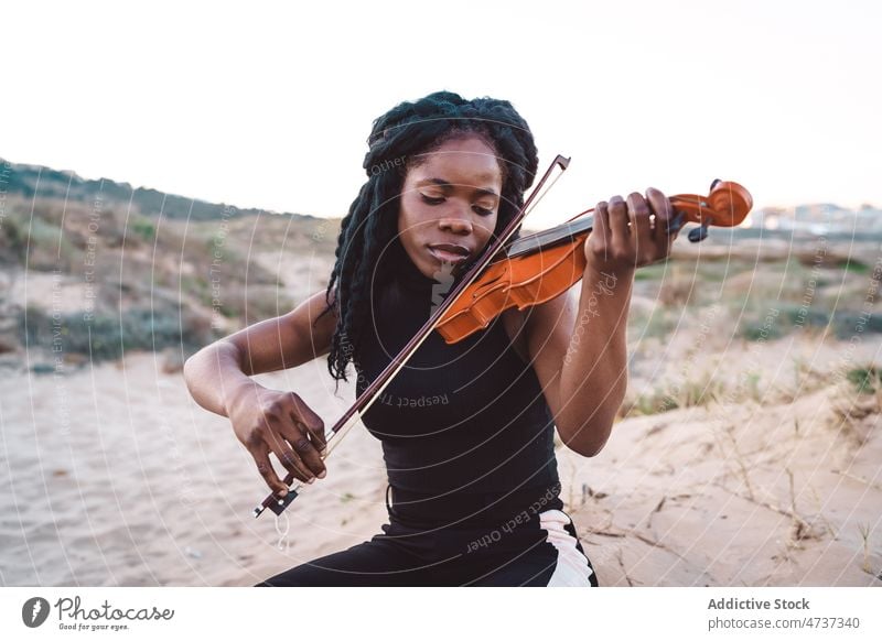 Dreamy black woman playing violin at seaside dreamy music beach musician melody instrument eyes closed female ethnic african american enjoy inspiration tranquil