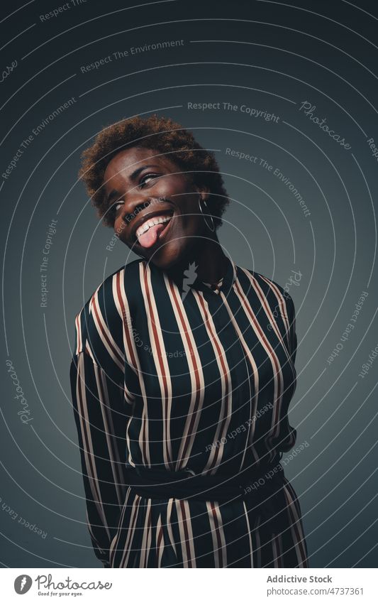 Funny black woman showing tongue in studio funny tongue out having fun make face playful grimace naughty pretend carefree female positive curly hair style
