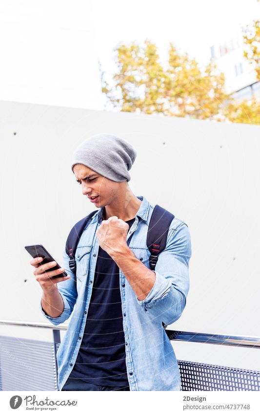 Outside portrait of modern young man with mobile phone in the street. 1 adult attractive backpack casual caucasian charming cheerful city clothing communication