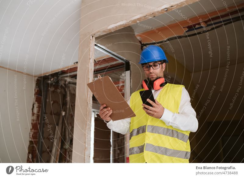 foreman or architect working on mobile phone blueprints .construction site. Home improvement technology internet house professional insulating ear defenders