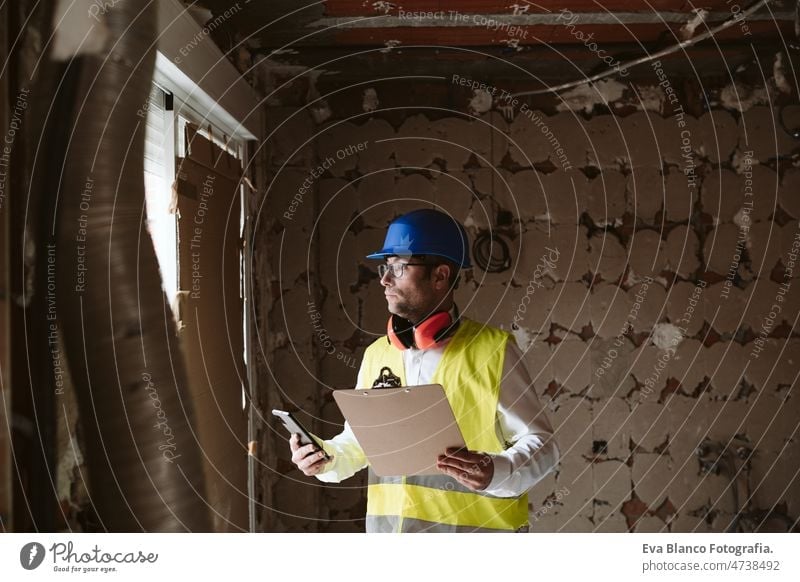 foreman or unrecognizable architect working on blueprints on construction site. Home improvement house professional insulating ear defenders worker industry