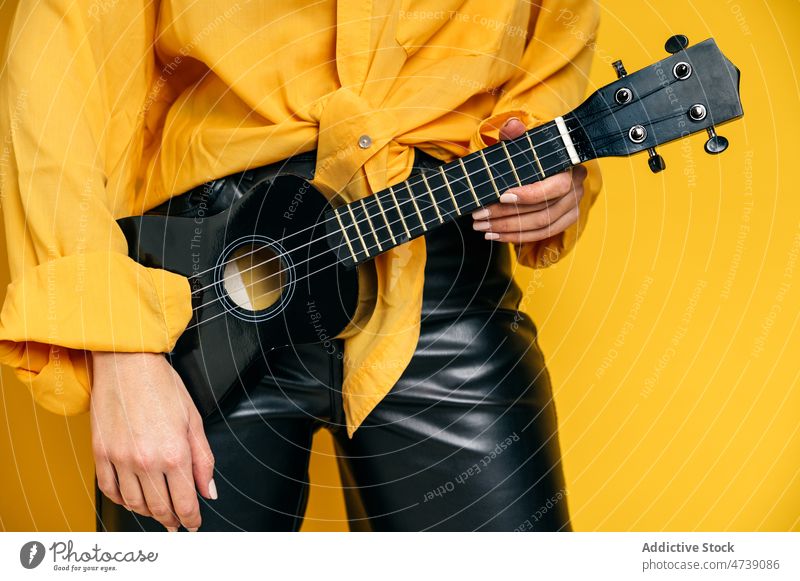 Stylish woman standing with ukulele in studio musician style acoustic hobby instrument practice create female editorial creative string melody skill talent