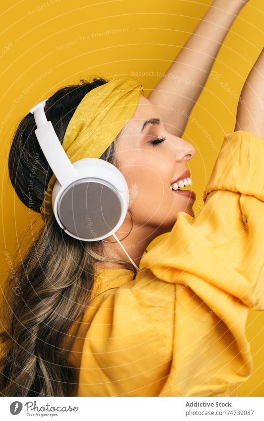 Delighted woman listening to music in headphones happy dance bright style cool leisure female editorial cheerful colorful joy energy positive hobby makeup model