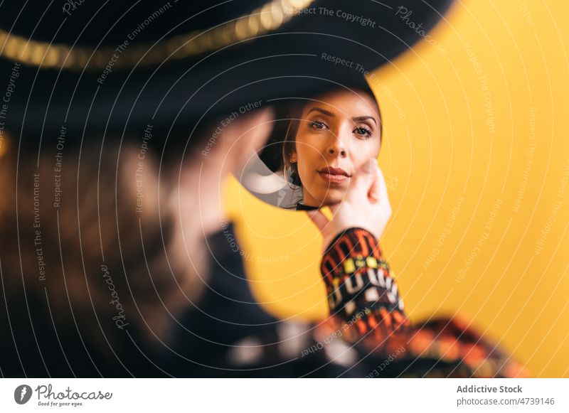 Trendy woman looking in mirror in studio reflect style fashion trendy hat reflection outfit charming female modern appearance round shape circle content model