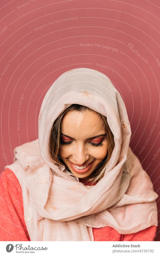 Attractive arab woman in headscarf in studio pink style makeup feminine design cover face enigma hide trendy appearance calm eyes closed female attractive timid