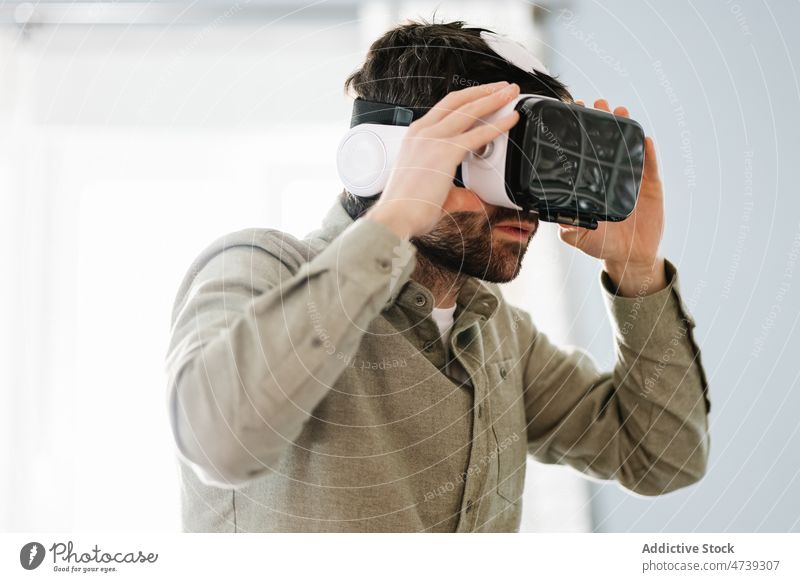 Serious ethnic man wearing VR goggles and looking away explore virtual reality concentrate innovation cyberspace adjust serious simulate immerse futuristic