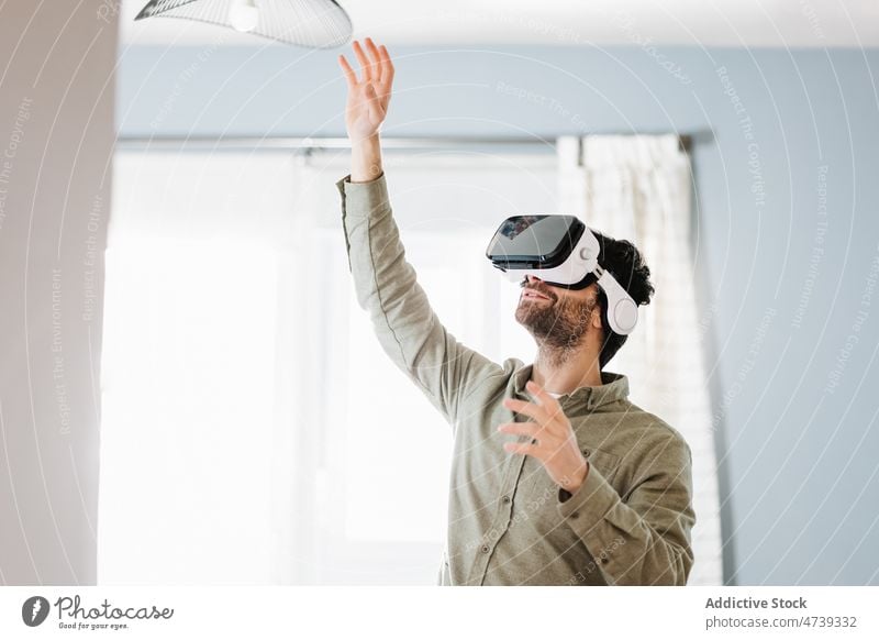 Young man exploring cyberspace in VR goggles at home virtual reality vr smile experience innovation gesture simulate entertain digital male young beard brunet