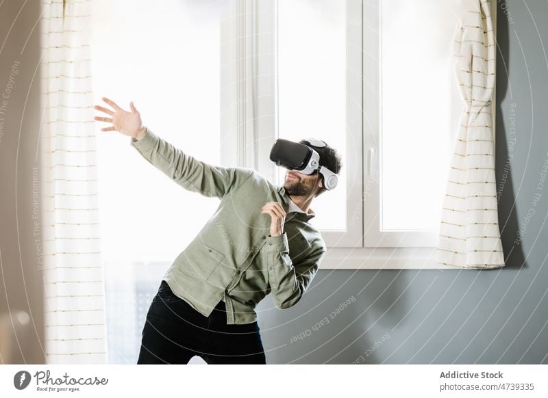 Young man exploring cyberspace in VR goggles at home virtual reality vr smile experience innovation gesture simulate entertain digital male young beard brunet