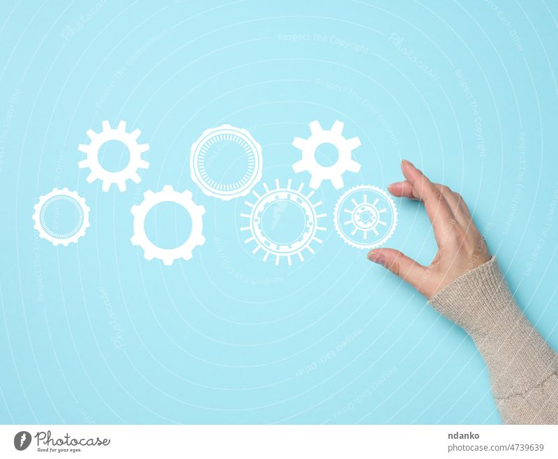 gear wheels and female hand on a blue background. Business structure precise work concept, team unification arm business cog cogwheel connection control