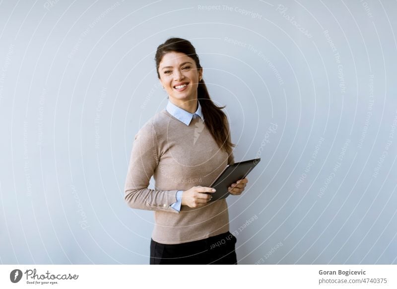 Young business woman standing by the white office wall and using digital tablet adult attractive businesswoman career caucasian checking single communication