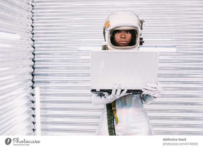 Black astronaut browsing laptop in spaceship woman spacesuit helmet cosmonaut online internet surfing mission uniform modern safety african american netbook