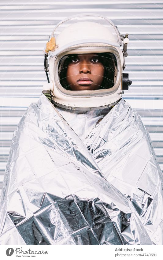 Black astronaut wrapped in emergence blanket woman spacesuit helmet spaceship cosmonaut emergency thermal safety costume mission survival uniform modern