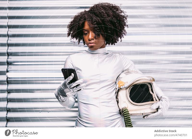 Black astronaut browsing smartphone in spaceship woman spacesuit helmet cosmonaut online internet surfing mission uniform modern safety african american black