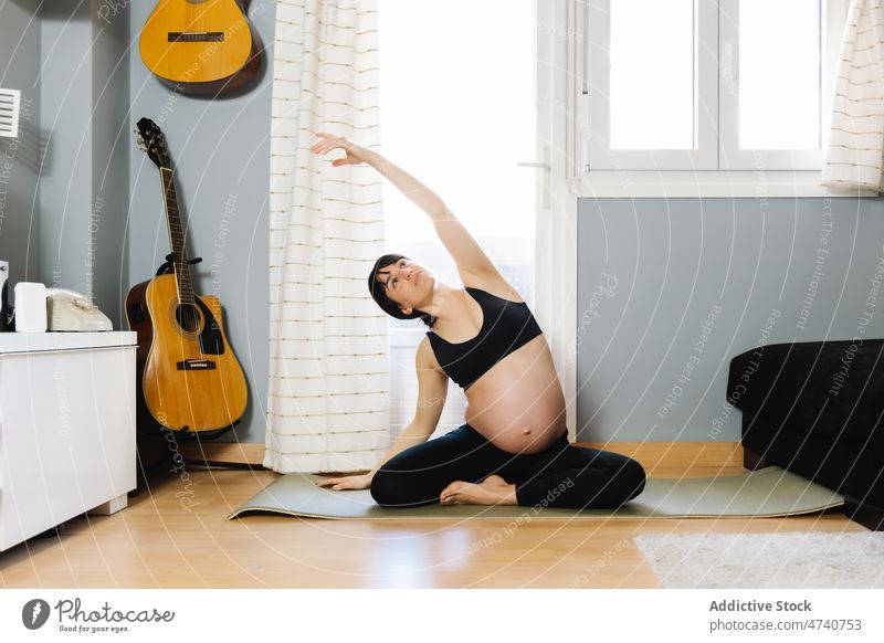 Pregnant woman doing yoga at home pregnant practice pregnancy expect flexible bend belly female stretch asana healthy prenatal sit mat maternal harmony tummy