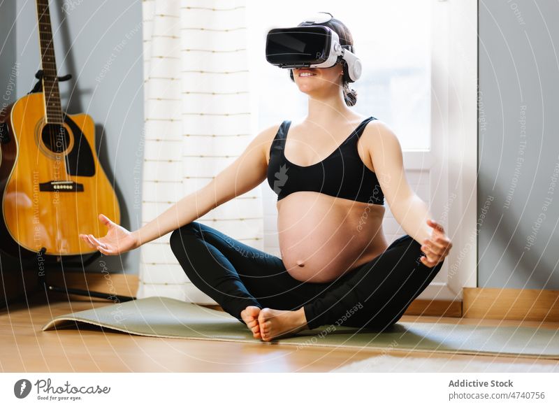 Smiling pregnant woman meditating in VR glasses at home yoga meditate vr cyberspace virtual reality pregnancy female goggles stretch cheerful practice