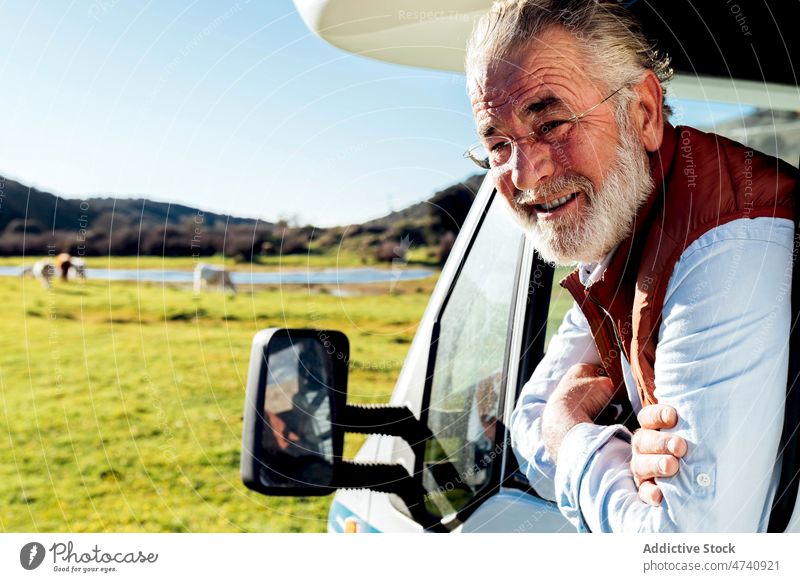 Man looking out window of trailer in nature man motorhome car rv camper field portrait road trip journey caravan observe countryside transport parked male auto