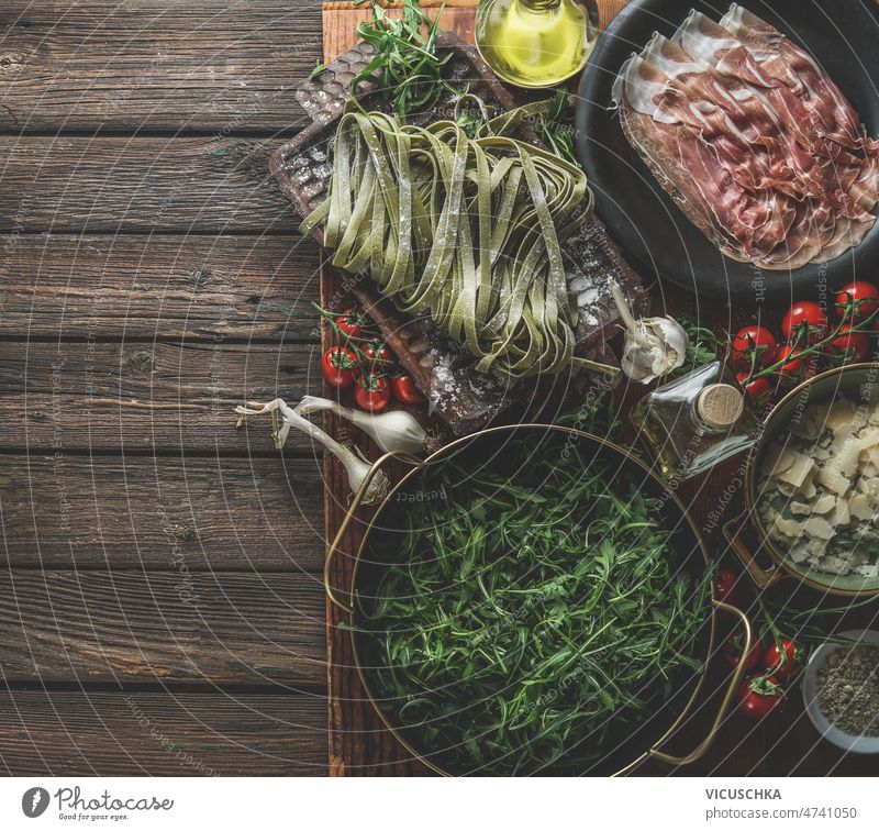 Italian food background with traditional ingredients on rustic wooden kitchen table italian food pasta parma ham arugula tomatoes parmesan cheese green