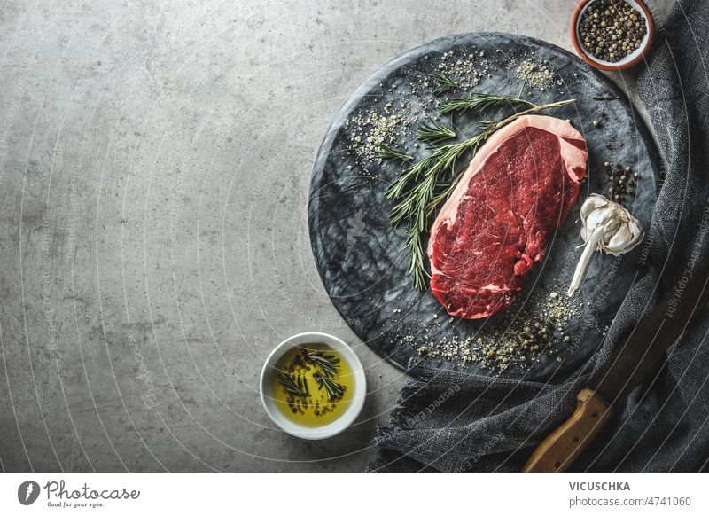 Food background with raw beef steak on marble cutting board raw meat food background rosemary garlic olive oil kitchen knife top view copy space cooking