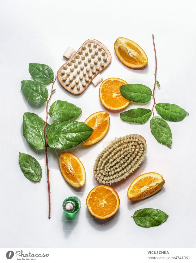 Dry brushing massage setting with body brushes for reduce cellulite with green leaves and orange slices at white background dry brushing wellness concept