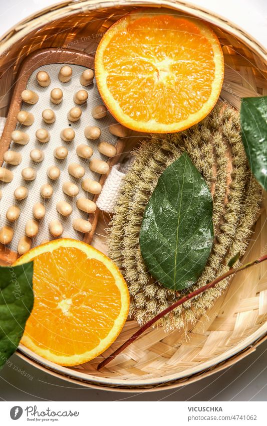 Close up of body brushes for dry brushing to reduce cellulite with green leaves and orange close up halves beauty concept natural sustainable equipment wellness