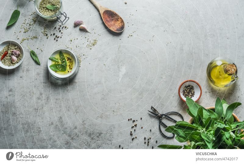 Food background with  flavorful ingredients at grey concrete table. Top view. food background herbal salt sage olive oil spices wooden cooking spoon