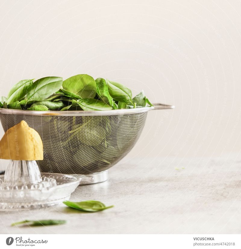 Food background with spinach leaves in sieve, lemon and citrus squeezer on kitchen table food background wall background healthy nutritious front view beige