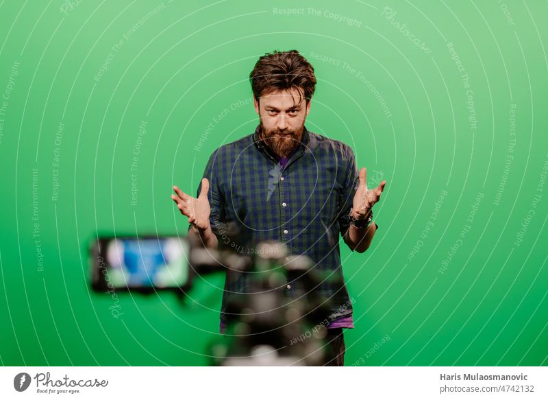 youtuber recording on green screen in studio adult attractive background beard broadcast broadcasting casual caucasian confident digital earphone equipment guy