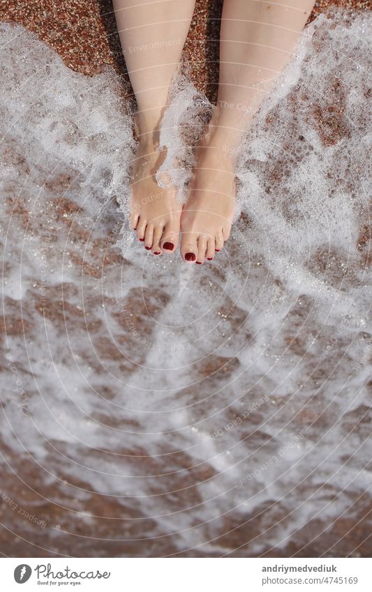 Travel concept - Woman's legs on beautiful tropical beach with pebble sand. Feet on sand and wave in summer time. girl barefoot in ocean water on vacation travel. Feel happy and relax. copy space.