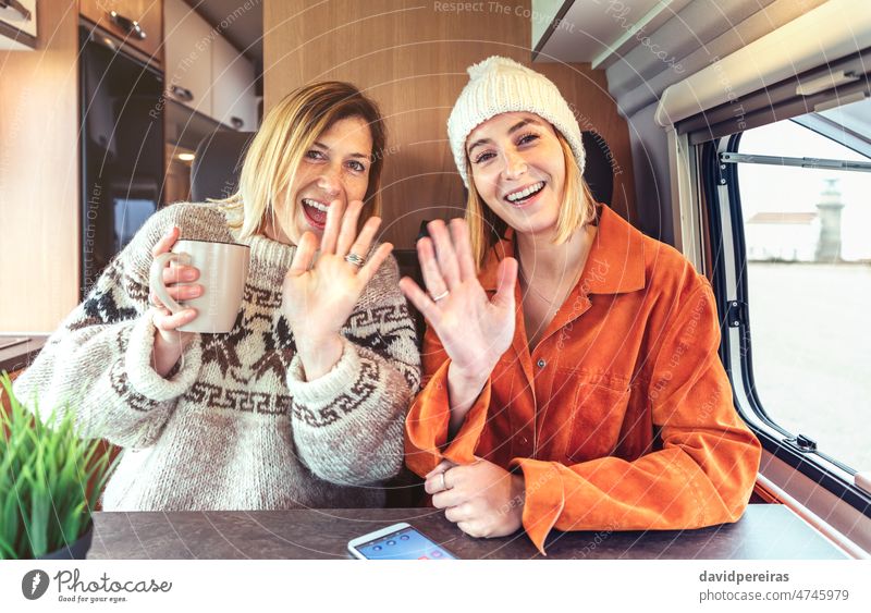 Happy women waving looking at camera on video call from their campervan happy looking camera smiling travel camper van friends sisters hand person talking