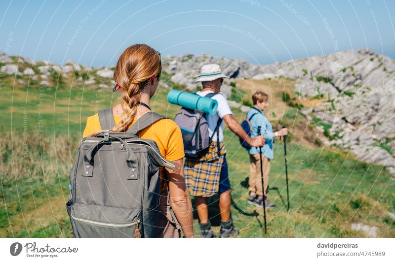 Senior couple with their adult daughter on their backs hiking unrecognizable senior family trekking backpack group walk mature father mother nature rock elderly