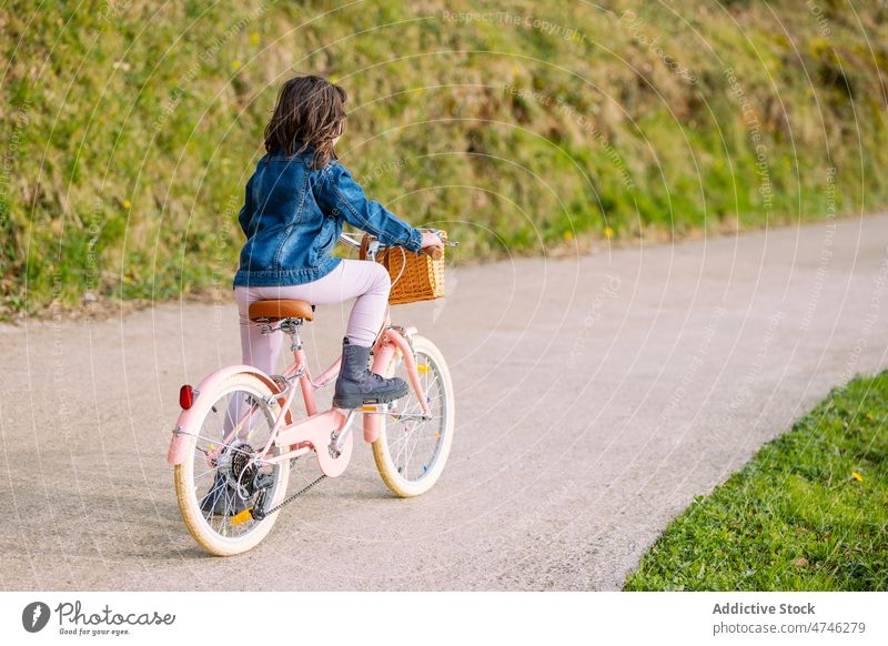 Anonymous kid riding bicycle on path park hobby leisure pastime childhood recreation ride activity summer bike transport summertime plant cute adorable