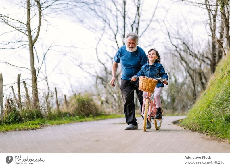 Grandfather teaching girl riding bicycle in countryside grandfather hobby leisure childhood spend time ride help spare time man care learn activity kid