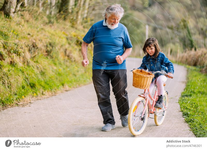 Grandfather running with granddaughter riding bicycle grandfather girl hobby leisure childhood spend time ride countryside energy action spare time man
