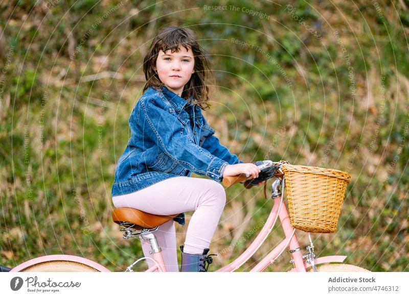 Cute girl sitting on bicycle kid park hobby leisure pastime childhood recreation ride basket activity summer bike transport summertime cute adorable entertain
